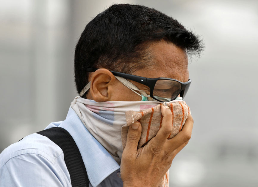 Man covers his face as he walks to work in Delhi. Man covers his face as he walks to work in Delhi.